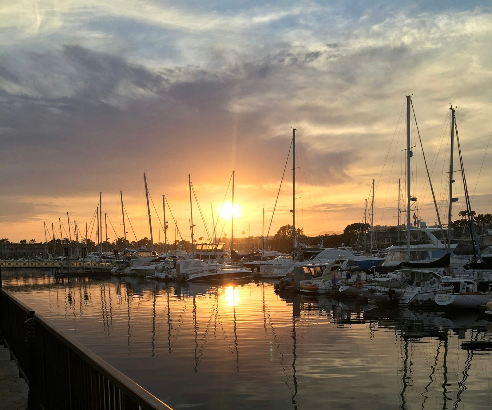 Sailboats docked in Marina del Rey harbor under a cloudy sky